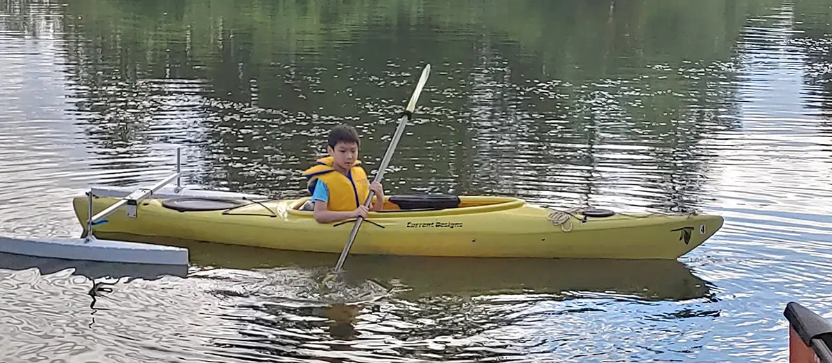a child paddling in a yellow kayak