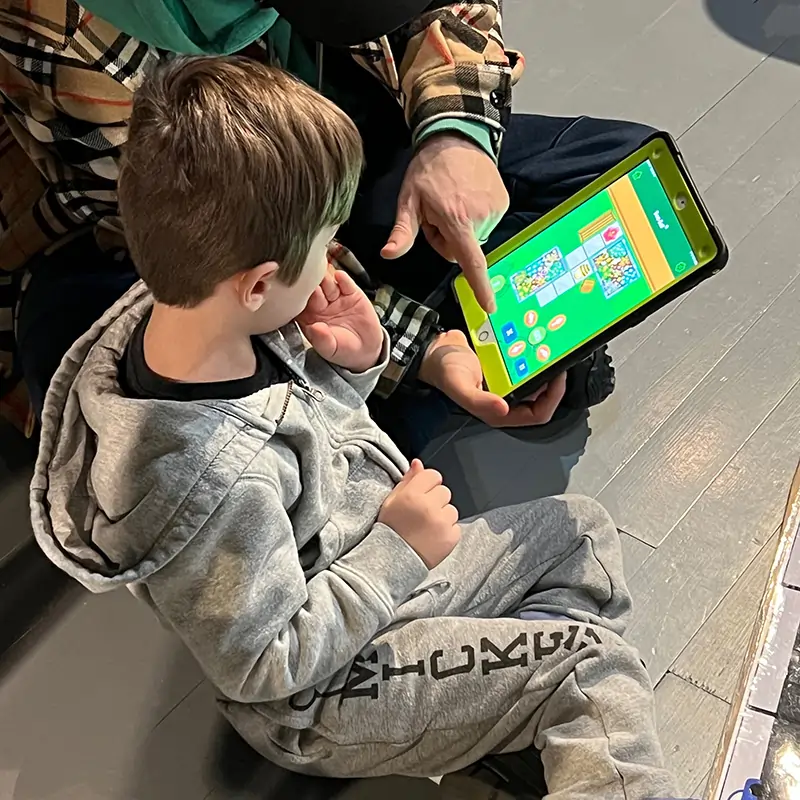 an adult showing a kid how to play a game on a tablet